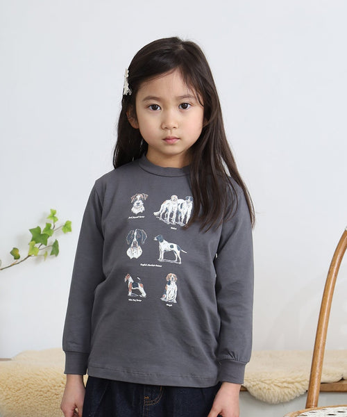 スミクロのBritish Dogsキッズ長袖Tシャツを着た女の子。犬種図鑑風イラストのプリントが見える